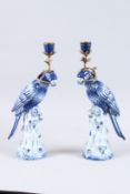 A GOOD PAIR OF SEVRES DESIGN BLUE PARROT CANDLESTICKS standing on tree stumps. 14ins high.