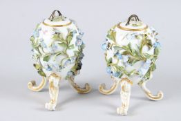 A PAIR OF MEISSEN FLOWER ENCRUSTED EGG SHAPED VASES AND COVERS on three curving legs. 5.5ins high.
