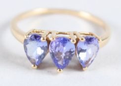 A 10CT GOLD THREE STONE TANZANITE RING.