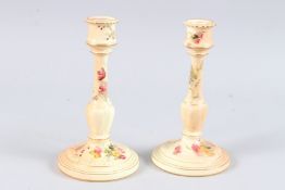 A PAIR OF ROYAL WORCESTER CANDLESTICKS painted with flowers. 8ins high.