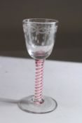 A 19TH / EARLY 20TH CENTRURY CORDIAL GLASS with engraved bowl and coloured air twist stem.