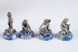 A SET OF FOUR RUSSIAN LAPIS AND SILVER CUPIDS, each 2ins high, in a Faberge box.