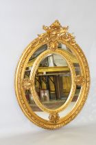 A LOUIS XVITH STYLE GILTWOOD OVAL MIRROR with shell motif. 4ft 7ins high x 2ft 10ins wide.