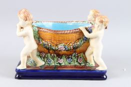 A MAJOLICA STYLE POTTERY CHERUB PLANTER on a blue base. 12ins high.