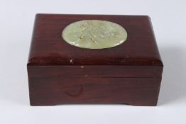 A CHINESE WOODEN BOX, the lid with a carved oval jade plaque. Jade 2.75ins x 2ins.