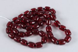 A CHINESE STRING OF CHERRY AMBER BEADS. 30ins long.