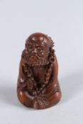 A CARVED HARDWOOD SEATED SAGE. 2.5ins.