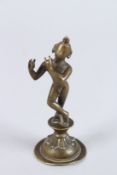 AN INDIAN BRONZE FIGURE OF THE HINDU GOD KRISHNA in his youthful form, on a circular base. 5ins