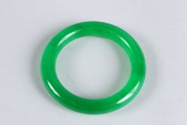 A CHINESE APPLE GREEN JADE BANGLE. 3.25ins diameter.