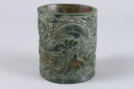 A CHINESE CARVED JADE BRUSH POT, the sides carved with dragons. 6ins high x 5ins diameter.