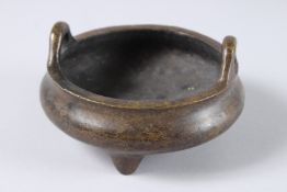 A CHINESE TWO HANDLED BRONZE CENSER, six impressed marks. 5.5ins diameter.