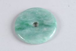 A CIRCULAR MOTTLED JADE PENDANT. 2ins diameter.