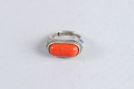 A CHINESE CORAL SADDLE RING.