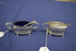 A silver salt with spoon and matching mustard pot with spoon, both with blue glass liners.