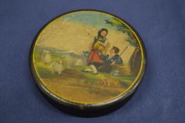 A small circular lacquered papier mache snuff box, the cover decorated with a young couple and