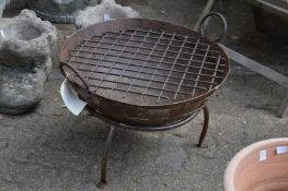 A wrought iron fire pit with griddle.