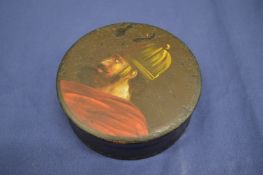 A black lacquer papier mache circular snuff box, cover decorated with a portrait bust of a man,