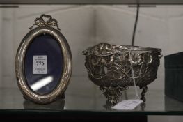 A small silver oval photograph frame and a plated basket with glass liner.