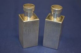 A pair of white metal square shaped scent bottles.