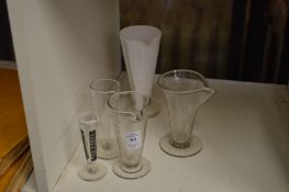 Five various etched glass medicine measures.