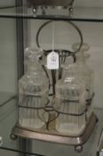 A plated four bottle decanter stand with a set of four cut glass decanters, two lacking stoppers.