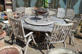 A large circular wooden garden table with a set of six folding armchairs and Lazy Susan