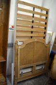 A pair of cane work single bed head boards and a white painted single bed frame.