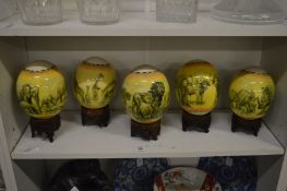 A set of five egg shaped ornaments on stands painted with African animals.