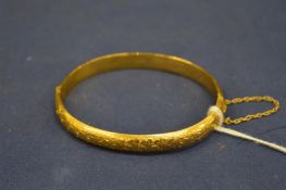 A 9ct gold bangle with engraved decoration.