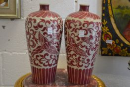 A pair of Chinese meiping shaped vases decorated in copper red depicting phoenix's.