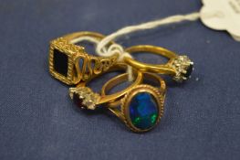 A group of four gold and gem set rings.