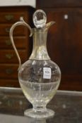 A plain glass claret jug with silver mounts.
