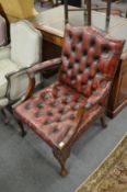 A burgundy leather button upholstered open armchair.