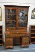 A George III mahogany secretaire kneehole bookcase with pair of glazed doors and two drawers above a