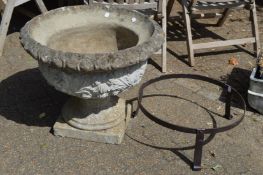 A large classical style composite pedestal urn with associated wrought iron stand.