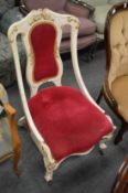A Victorian nursing chair with white painted frame.