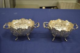 A good pair of chased and engraved silver twin handled bowls on scroll feet.