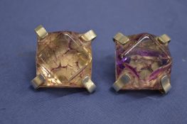 A pair of chunky silver ear clips with amethyst colour stones.