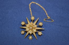 A yellow metal and pearl star shaped brooch.