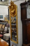 A pair of decorative gilt framed narrow mirrors with figural decoration.