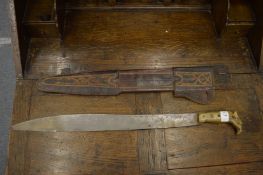 A horn handled short sword or machete with decorative leather scabbard.