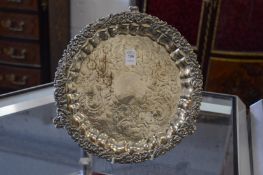 Decorative silver plated salver with engraved decorated centre and cast border with scroll feet.