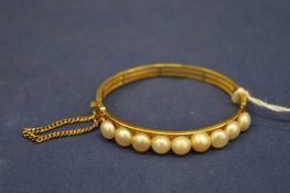 A yellow metal and pearl bangle stamped 22.