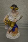A small 19th century porcelain figure of a boy standing next to a beehive.