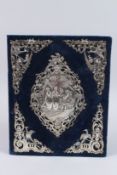 A VICTORIAN SILVER MOUNTED BLUE VELVET DESK BLOTTER/ALBUM, the central embossed silver panel