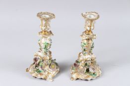 A PAIR OF JACOB PETIT FLORAL ENCRUSTED PORCELAIN CANDLESTICKS (af), 10in high.