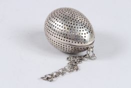 A SILVER EGG SHAPED TEA STRAINER, appears unmarked, 2¾in long.