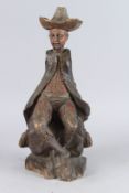 AN EARLY CARVED WOOD FOLK ART FIGURE of a seated man. 16ins high.