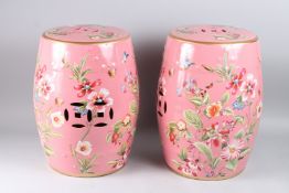 A PAIR OF CHINESE STYLE PINK PORCELAIN BARREL SEATS, decorated with flowers and insects, 18in high.
