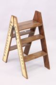 A PAIR OF NOVELTY FOLDING WOODEN STEPS, advertising various makes of champagne, 2ft 8in high.